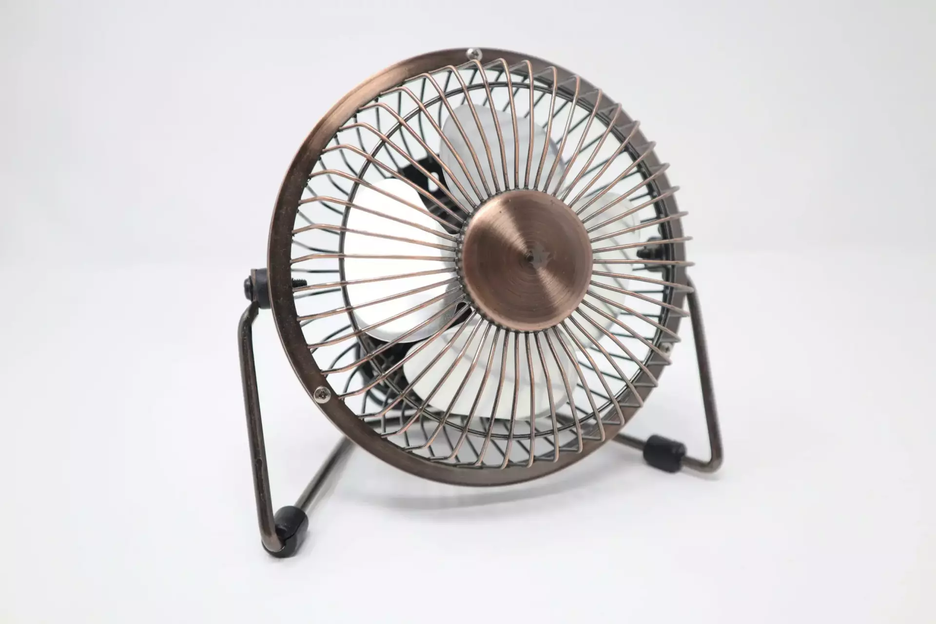 call-me-fred-6KZcjJoaqNI-unsplash Kleiner Tischventilator aus Metall mit bronzefarbenem Finish auf weißem Hintergrund. Ideal für Schreibtische.