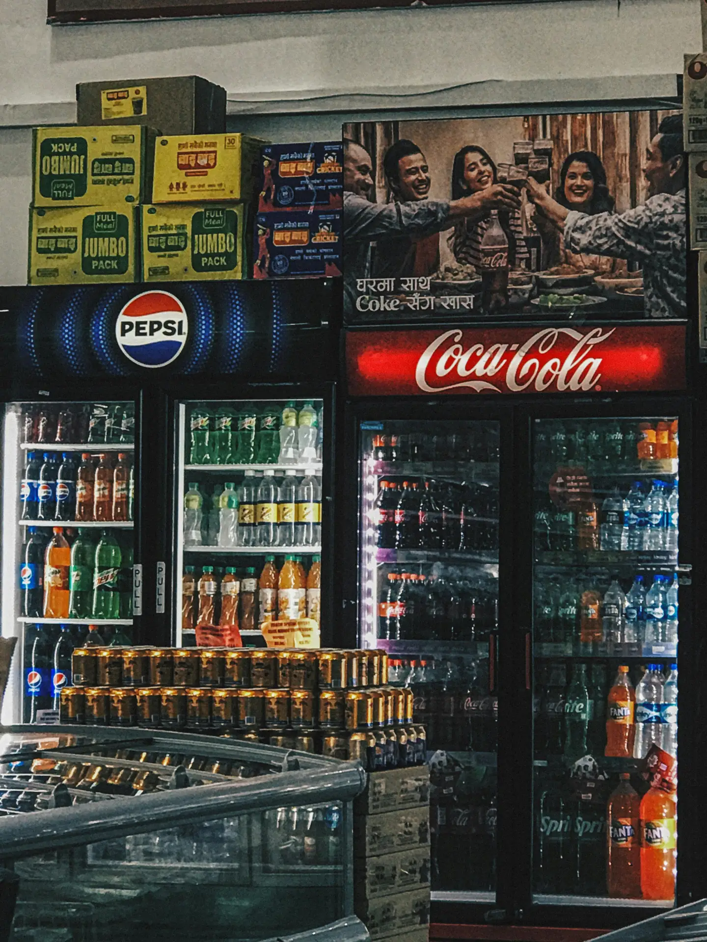 pexels-yogyata-roka-2151488823-34191048 Kühlschrank mit Pepsi und Coca-Cola in einem Geschäft, umgeben von Getränkedosen und Produktverpackungen.