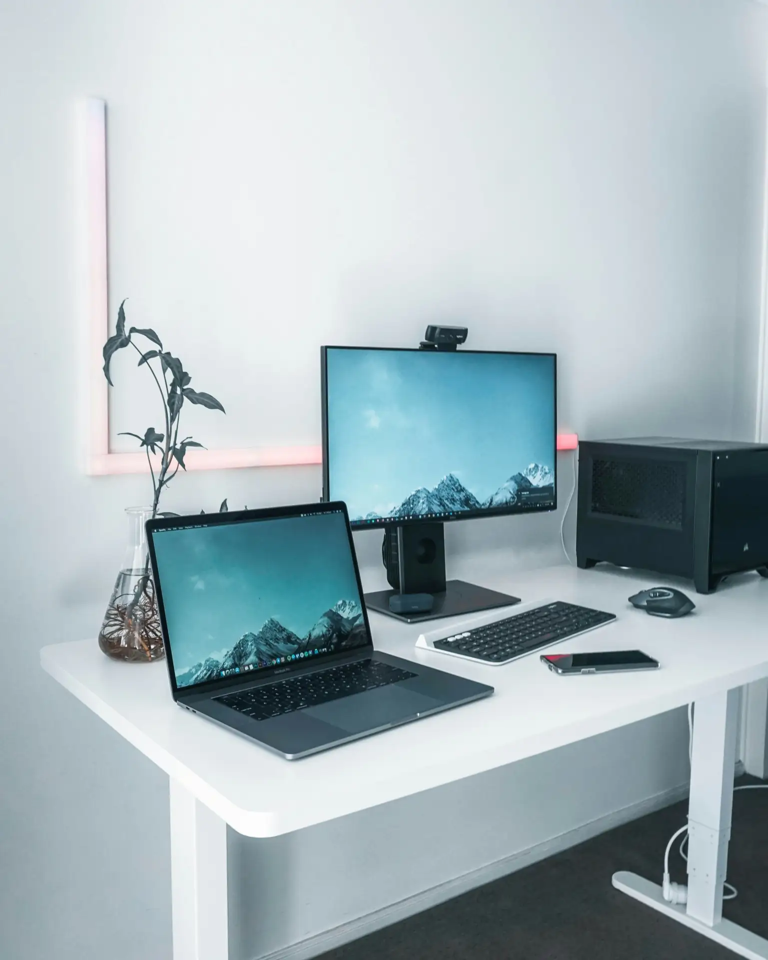 tarn-nguyen-XlEafYGDvV0-unsplash Moderner Schreibtisch mit Laptop, Monitor und Pflanzen, minimalistisch eingerichtet im Büro mit LED-Beleuchtung.